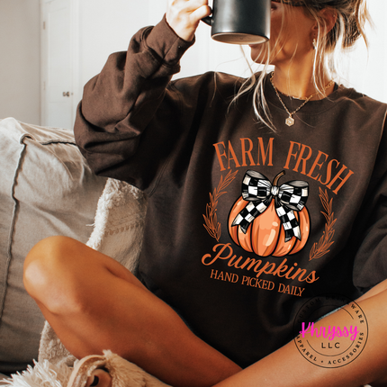 Woman wearing a dark chocolate crewneck sweatshirt with a pumpkin design.