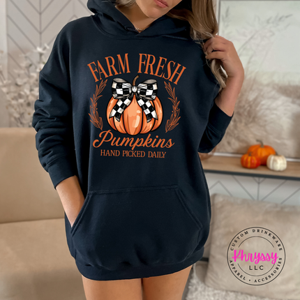 Woman wearing an black pullover hoodie with a pumpkin design.