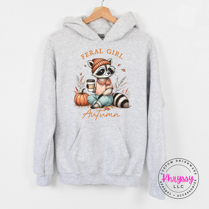 Ash colored hoodie featuring a feral girl autumn raccoon illustration.