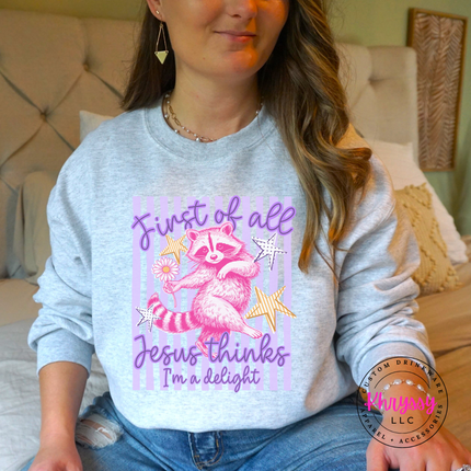 Person wearing a gray sweatshirt with a colorful graphic and text, sitting on a bed.