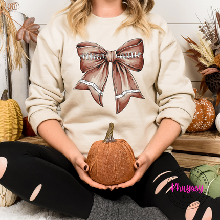 Sand crewneck with a cute football bow game day graphic.