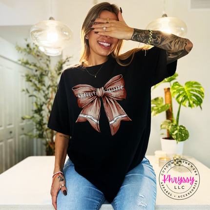 Close-up of a football lace bow graphic on a Black cotton tee.