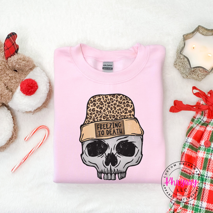 Close up of the Freezing To Death beanie patch on a Light Pink crewneck sweatshirt.