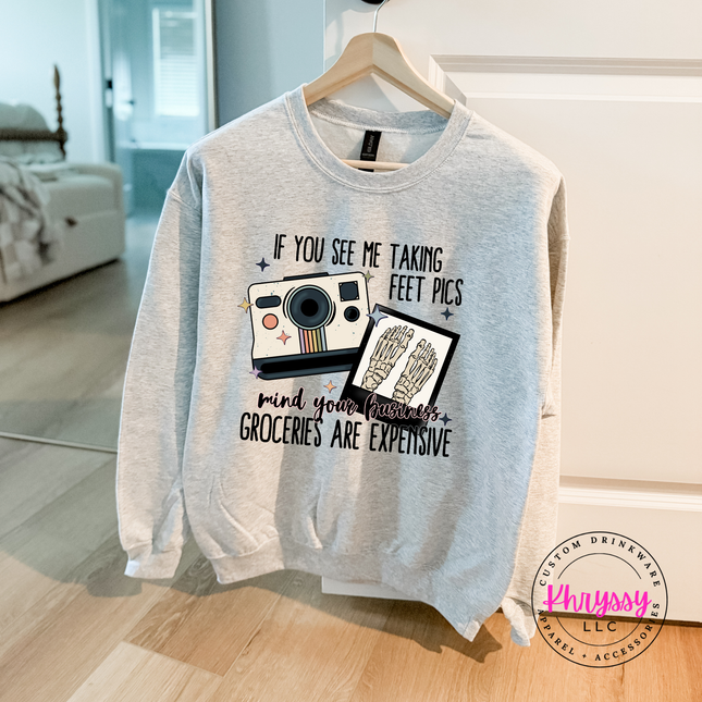 Gray sweatshirt with graphic design and text on a hanger in a room.
