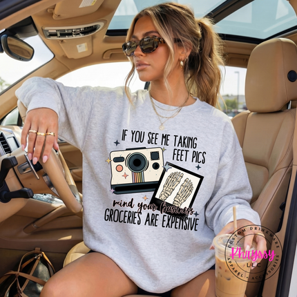 Woman sitting in a car wearing a sweatshirt with a camera graphic and text.