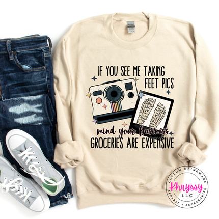 Sand sweatshirt with graphic design and text, paired with jeans and sneakers on a white background.