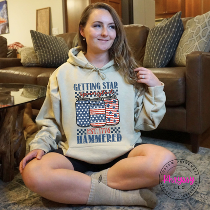 Sand pullover hoodie displaying a vintage patriotic beer-can graphic with white stars.