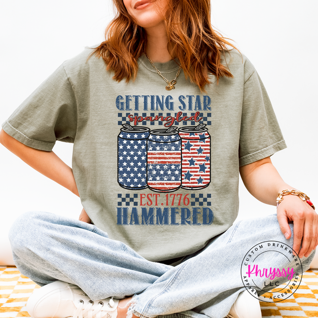 Sandstone garment-dyed tee with a faded star-spangled hammered beer-can design.