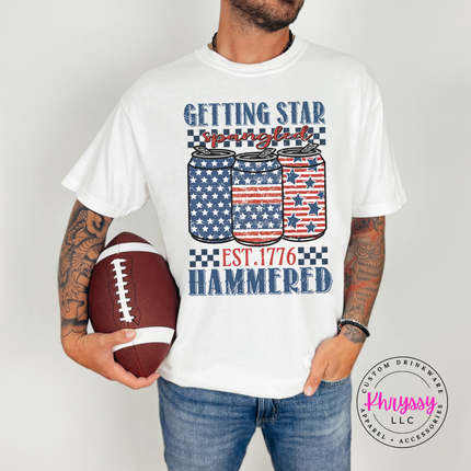 White garment-dyed tee displaying a vintage patriotic beer-can graphic with white stars.