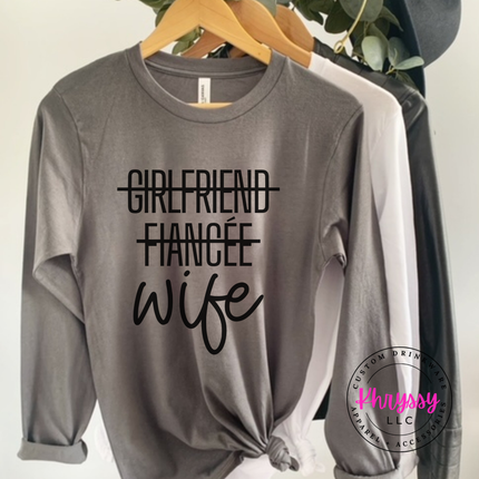 Gray sweatshirt with 'Girlfriend Fiançée Wife' text on a hanger, Phrysy LLC logo visible.
