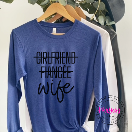 Blue long-sleeve shirt with 'Girlfriend Fiancée Wife' text on a hanger.