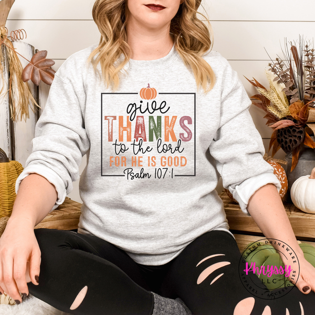 Woman wearing an Ash crewneck sweatshirt with a Give Thanks Psalm 107 graphic.
