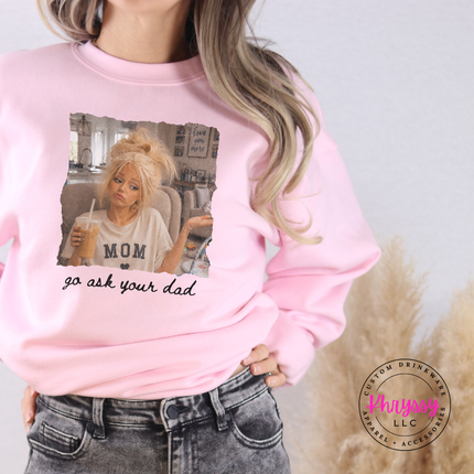 Person wearing a pink sweatshirt with a graphic and text, standing against a neutral background.