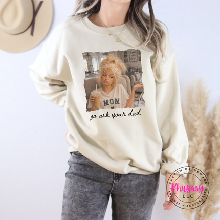 Person wearing a cream sweatshirt with a graphic and text, standing against a light background.