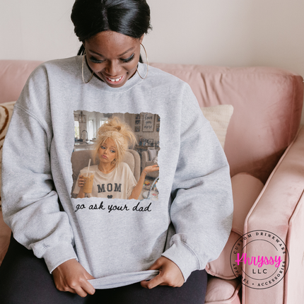 Person wearing a gray sweatshirt with a graphic design, sitting on a pink couch.
