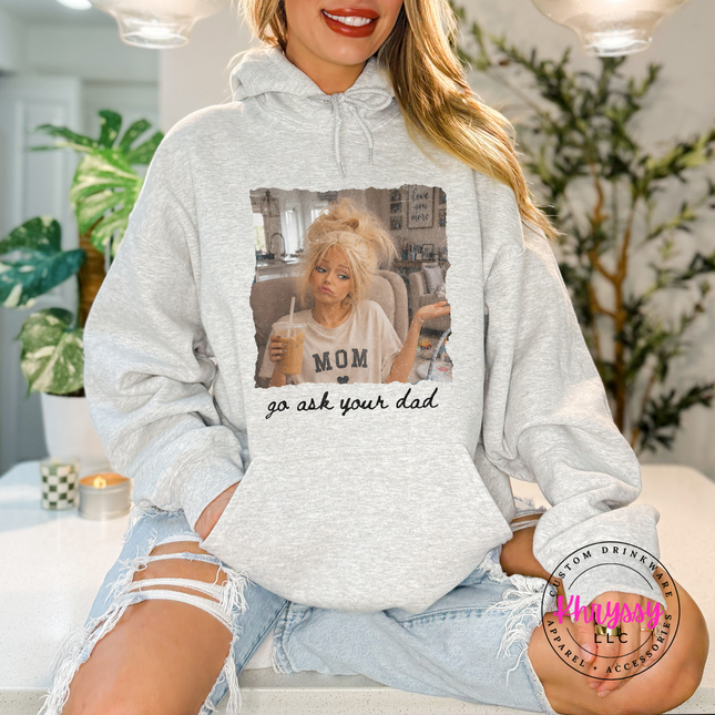 Person wearing a gray hoodie with a graphic design, sitting indoors.