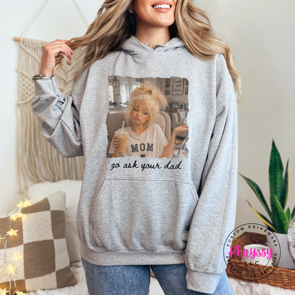 Person wearing a gray hoodie with a graphic design and text, standing in a cozy indoor setting.