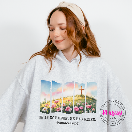 Ash pullover hoodie with a He Has Risen watercolor cross and wildflowers graphic.