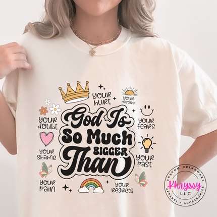 Ivory garment-dyed tee showing a black God Is So Much Bigger Than faith print.
