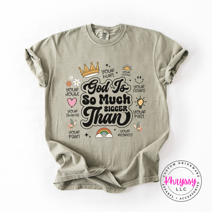 Sandstone garment-dyed tee with an encouraging God Is So Much Bigger Than graphic.