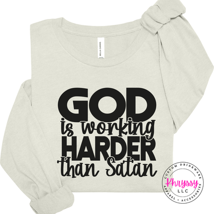 Natural long sleeve tee with an all-caps God Is Working Harder design