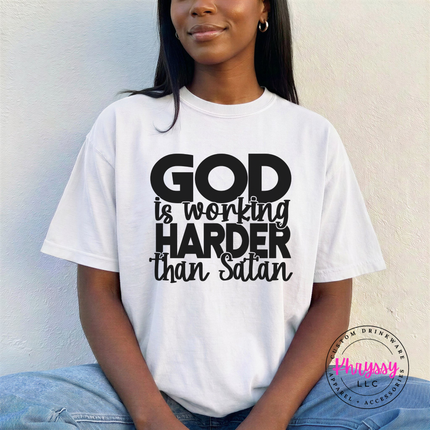 White tee with confident black God Is Working Harder Than Satan lettering