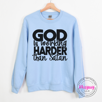 Light Blue crewneck sweatshirt with an all-caps God Is Working Harder design