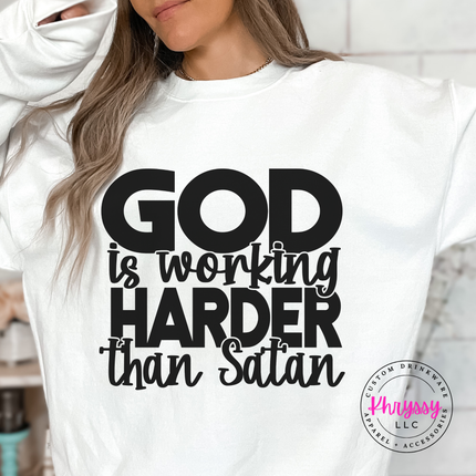 White crewneck sweatshirt with confident God Is Working Harder lettering