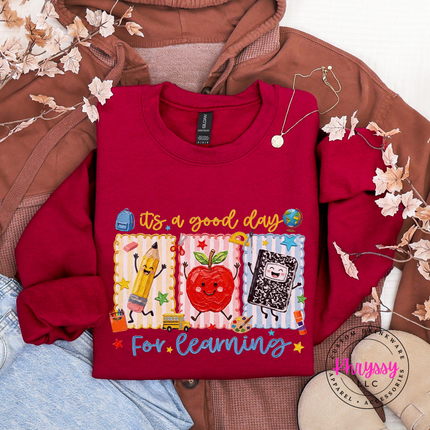 Cherry red heavyweight crewneck with colorful pencil, apple, and notebook print.