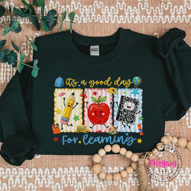 Forest green Gildan crewneck featuring a smiling apple and dancing pencil design.