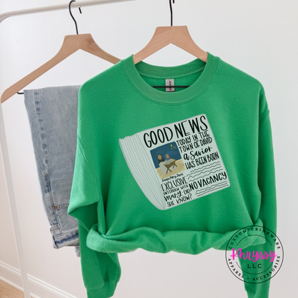 Flat lay of the Good News nativity Christmas crewneck sweatshirt in Irish Green.