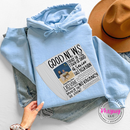 Light Blue hoodie showing a Good News newspaper with a nativity photo.