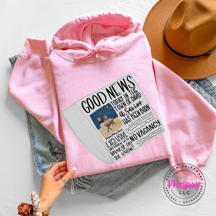 Flat lay of the Good News nativity Christmas hoodie in Light Pink.