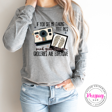 Person wearing a gray sweatshirt with a graphic and text, standing against a plain background.
