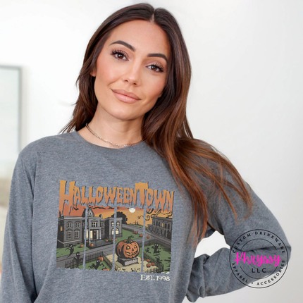 Woman wearing an Athletic heather Bella+Canvas long sleeve with a Halloweentown spooky graphic.