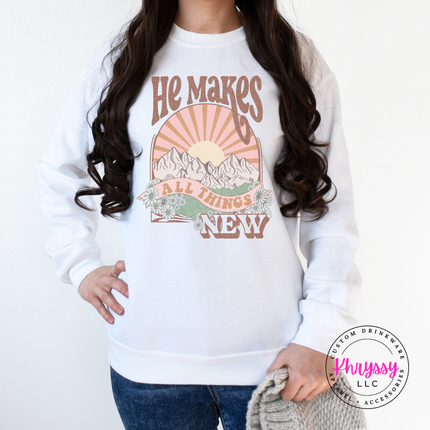 White heavyweight crewneck printed with a boho He Makes All Things New graphic.