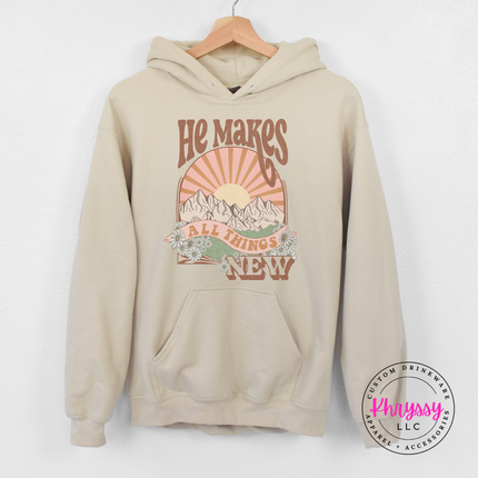 Sand heavyweight hoodie printed with a boho He Makes All Things New graphic.