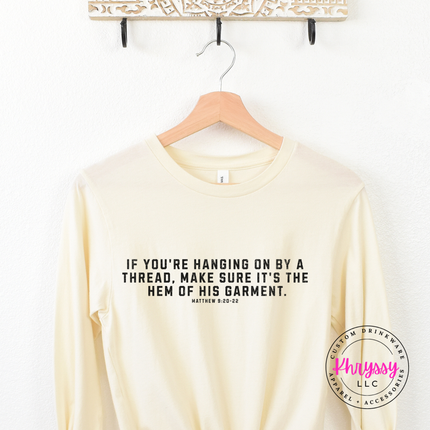 Natural long sleeve tee on a hanger with the hem of His garment verse