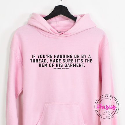 Light Pink hoodie printed with a black hem of His garment faith quote