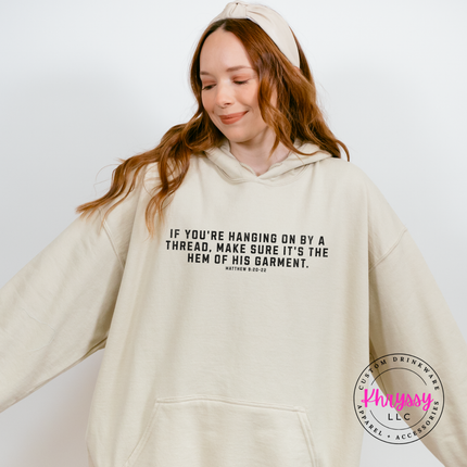 Sand hoodie styled flat with black hanging on by a thread scripture