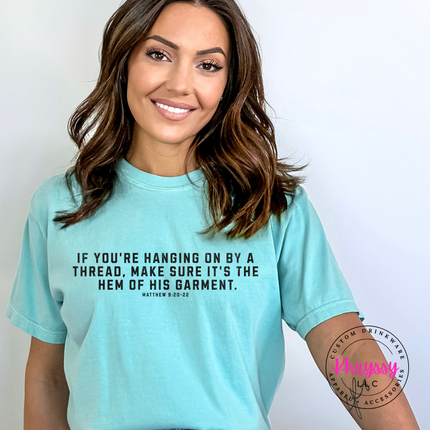 Folded Lagoon tee showing the hem of His garment scripture in black lettering