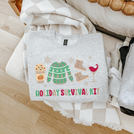 Ash crewneck sweatshirt featuring festive survival kit icons and lettering.