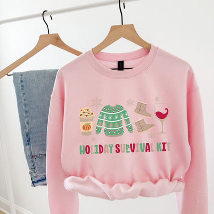 Flat lay of the Holiday Survival Kit Christmas crewneck sweatshirt in Light Pink.