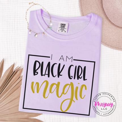 Orchid tee showing bold Black Girl Magic empowerment lettering in gold.