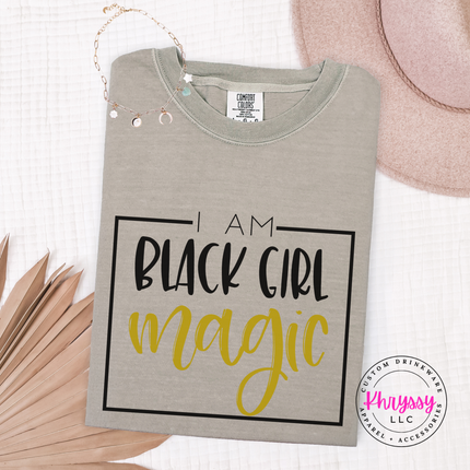 Sandstone tee with a black square frame and gold magic script.