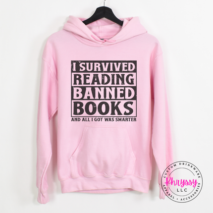 Light pink Gildan hoodie showing the bold dark distressed banned books reader graphic.