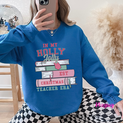 Close up of the Christmas teacher era book design on a Sapphire crewneck sweatshirt.