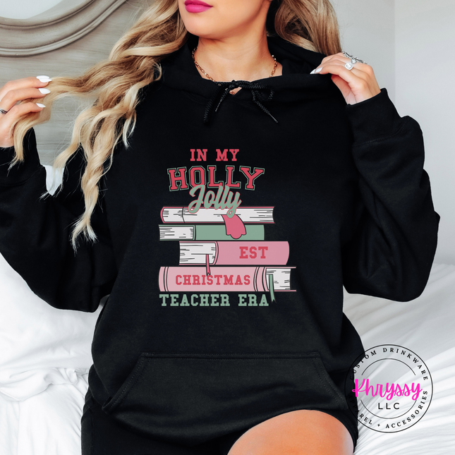 Holly Jolly Christmas Teacher Era book stack printed on a Black hoodie.