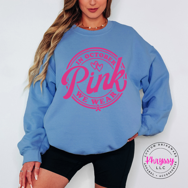 Woman wearing a Carolina Blue crewneck sweatshirt with the we wear pink badge
