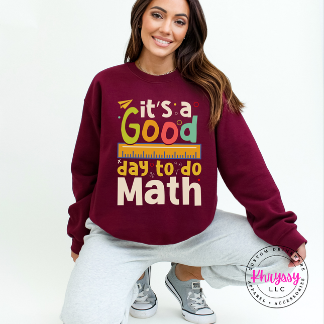 Maroon heavyweight crewneck showing bright multicolor math teacher statement with ruler and colorful letter detail.